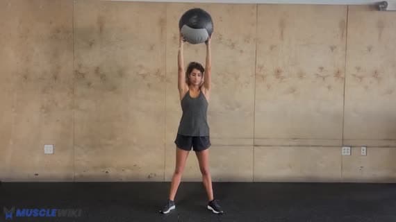 Squat avec ballon médicinal au-dessus de la tête