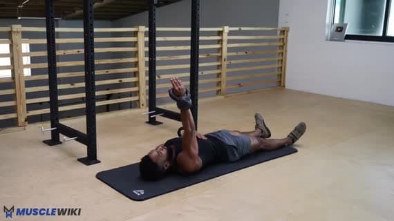 Crucifixo unilateral no chão com kettlebell